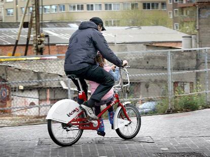 Un hombre con  un niña sentada en la barra de una bicicleta del <b>Bicing</b> en Barcelona.