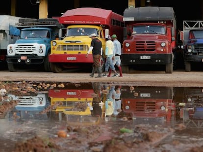 Um grupo de trabalhadores passa diante de caminhões em Havana.