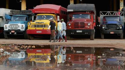 Um grupo de trabalhadores passa diante de caminhões em Havana.