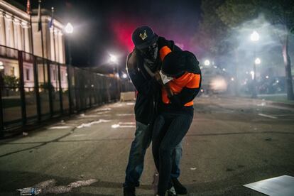 Homem socorre manifestante em Kenosha, Wisconsin, na terceira noite de protestos contra ação policial.