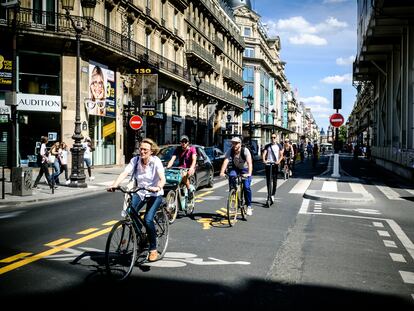 Parisienses percorrem a Rue de Rivoli de bicicleta.