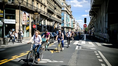 Parisienses percorrem a Rue de Rivoli de bicicleta.