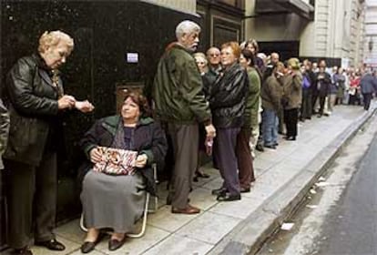 Pensionistas guardan cola frente al banco estatal para recibir su pensión mensual.