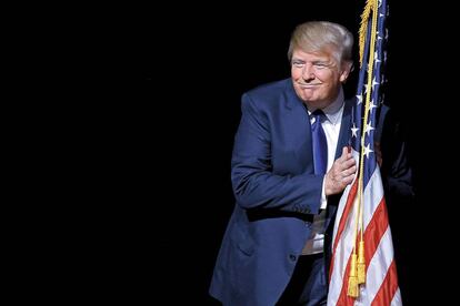 Donald Trump se abraza a la bandera estadounidense en un acto de la campaña celebrado en Derry, New Hampshire.