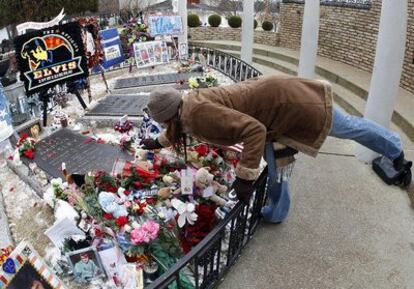 Una mujer deja flores en la tumba de Elvis Presley en Graceland.