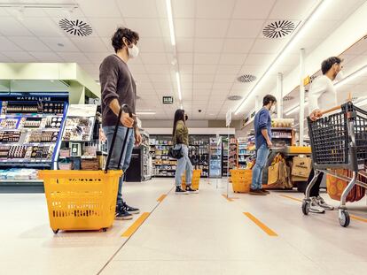 Compradores haciendo cola para pagar en un supermercado.