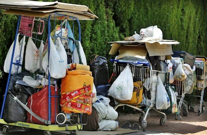 Una persona sin techo con sus pertenencias en carros junto al Jardí del Turia.