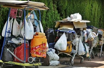 Una persona sin techo con sus pertenencias en carros junto al Jard&iacute; del Turia.