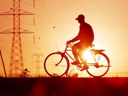 Un ciclista pasa junto a unas torres de alta tensión en las afueras de Nairobi, capital de Kenia.