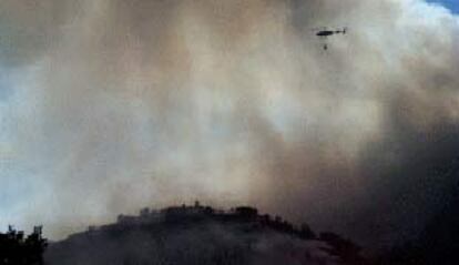 Un helicóptero de extinción de incendios sobrevolando ayer la zona afectada por el fuego en Bennifallim.