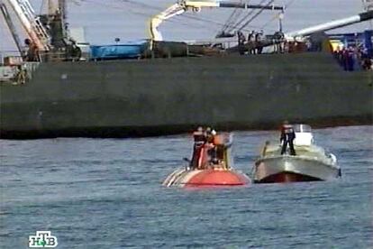 Una lancha de rescate se aproxima al pequeño submarino ruso (a la izquierda), con parte de su tripulación en la superficie.