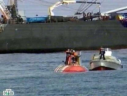 Una lancha de rescate se aproxima al pequeño submarino ruso (a la izquierda), con parte de su tripulación en la superficie.