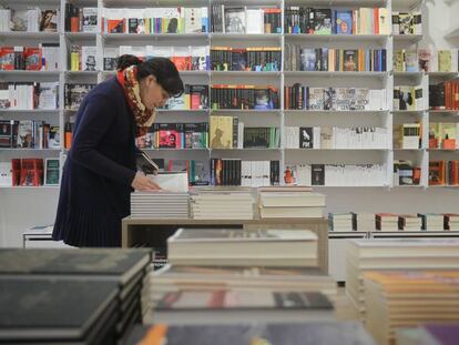 Una mujer hojea un libro en una librer&iacute;a de Barcelona.