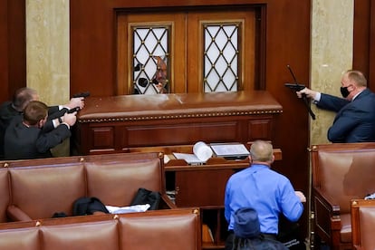 Los agentes de policía del Capitolio de Estados Unidos apuntaban con sus armas a la puerta principal de la Cámara de Representantes, mientras los miembros de una turba que apoyaba al presidente de Estados Unidos, Donald Trump, intentaban entrar, el 6 de enero de 2021 en Washington.