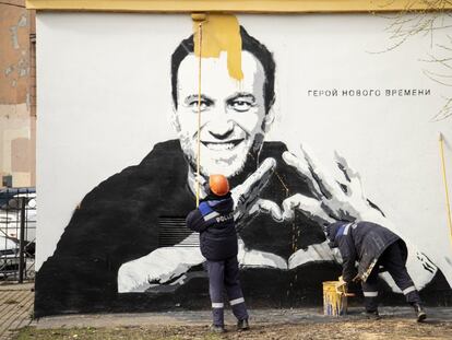 Trabajadores municipales quitan un grafiti del líder opositor ruso Alexéi Navalni, en el que se puede leer "héroe de nuestro tiempo", en San Petersburgo, el 28 de abril de 2021.