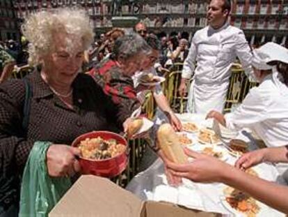 Una anciana recibe su plato de cocido en la plaza Mayor de Madrid. PLANO GENERAL - ESCENA