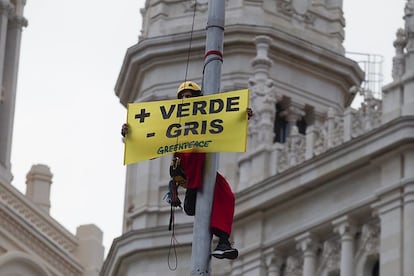 Un activista de Greenpeace, en una de las farolas que rodean la fuente de Cibeles durante esta mañana.