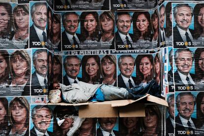 Un hombre sin hogar duerme debajo de los carteles del recién elegido presidente Alberto Fernández y su compañera de fórmula Cristina Fernández de Kirchner en un distrito comercial en Buenos Aires (Argentina).