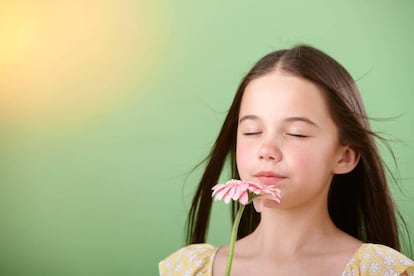 Una niña huele una flor.