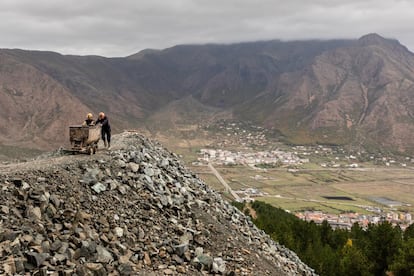 Dois mineiros empurram uma velha carroça, depois de descarregar minério de cromita da montanha de Bulqizë.