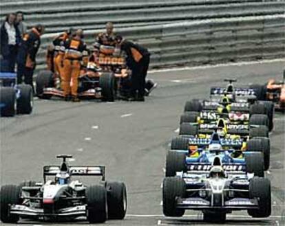 Ralf Schumacher, a la derecha, no puede arrancar al estar su coche suspendido sobre un <i>caballito</i>.