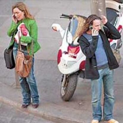 Personas hablando por el móvil en la Gran Vía de Madrid.