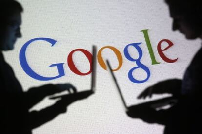 Dos internautas con sus portátiles, silueteados ante el logo de Google