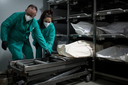Dos empleados preparan el cuerpo de un fallecido para introducirlo en un ataúd, en el tanatorio Sancho de Ávila, en Barcelona.