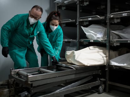 Funeral workers prepare to transfer a body to a coffin in Barcelona.