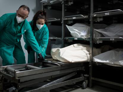 Dos empleados preparan el cuerpo de un fallecido para introducirlo en un ataúd, en el tanatorio Sancho de Ávila, en Barcelona.