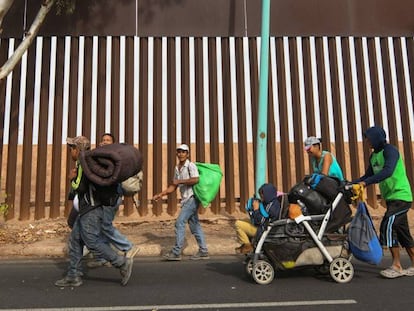 Migrantes centro-americanos caminham nesta terça-feira em Mexicali (México) ao lado da cerca na fronteira com os EUA.