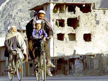 Vecinos de Kabul se desplazan en bicicleta por un barrio destruido en las sucesivas guerras.