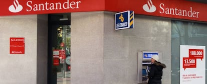 Una mujer retira dinero de un cajero automático en una oficina de Banco Santander.