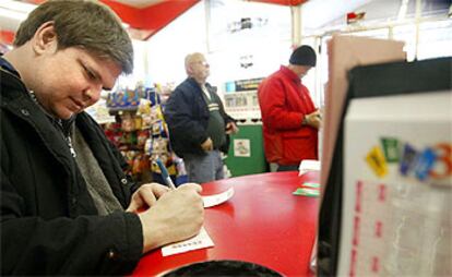 El joven Tim Vana rellena en una tienda su boleto de loto Powerball de Navidad.