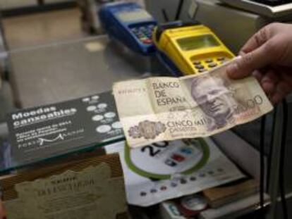 Un comerciante sostiene un billete de 5000 pesetas en un establecimiento de la localidad coruñesa de Mugardos. EFE/Archivo