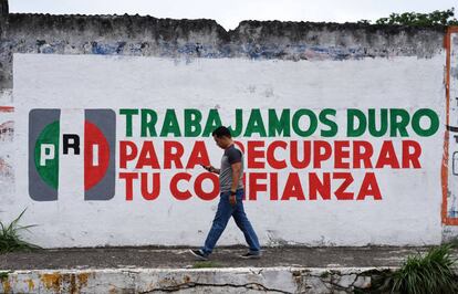 Un hombre camina por una calle del centro de la ciudad de Xalapa frente a un muro promocional del PRI el día 14 de junio de 2018.