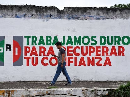Un hombre camina por una calle del centro de la ciudad de Xalapa frente a un muro promocional del PRI el día 14 de junio de 2018.