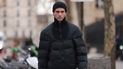 Un chico joven con un abrigo acolchado y gorro en invierno.