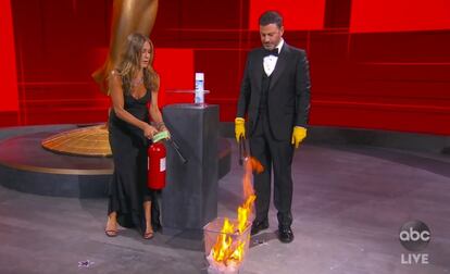 Jennifer Aniston, izquierda, y Jimmy Kimmel desinfectan un sobre con el nombre del ganador de un premio Emmy.