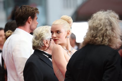 Anya Taylor-Joy turns around to pose on the 'Furiosa' red carpet.  Behind her, George Miller and Chris Hemsworth.
