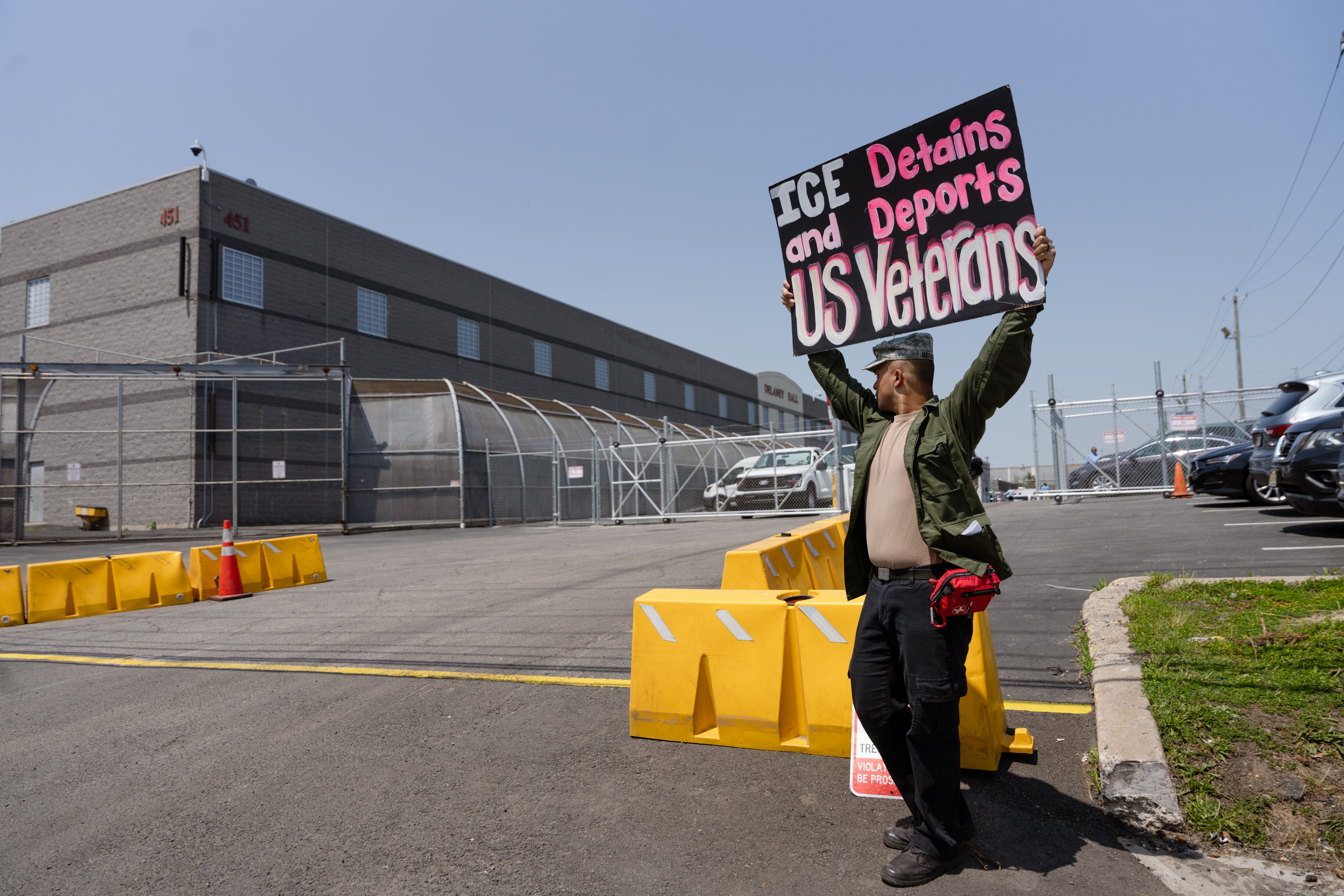 Adam M. protesta frente al centro de detención en contra de las detenciones y deportaciones de veteranos estadounidense.