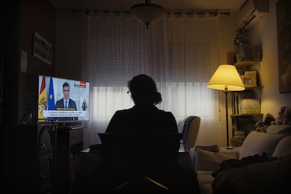 A woman watches Spanish Prime Minister Pedro Sánchez announce an extension to the state of alarm on March 28 and the freezing of all non-essential activity.