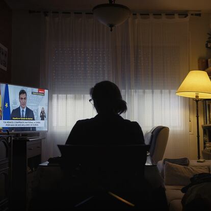 Una mujer ve en televisión a Pedro Sánchez anunciando, el 28 de marzo, la ampliación del estado de alarma y el cese de todas las actividades.