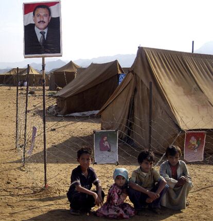Un grupo de niños del campo de refugiados de Mazraq, al norte de Yemen, permanecen sentados bajo una imagen del presidente yemení, Ali Abdullah Saleh.