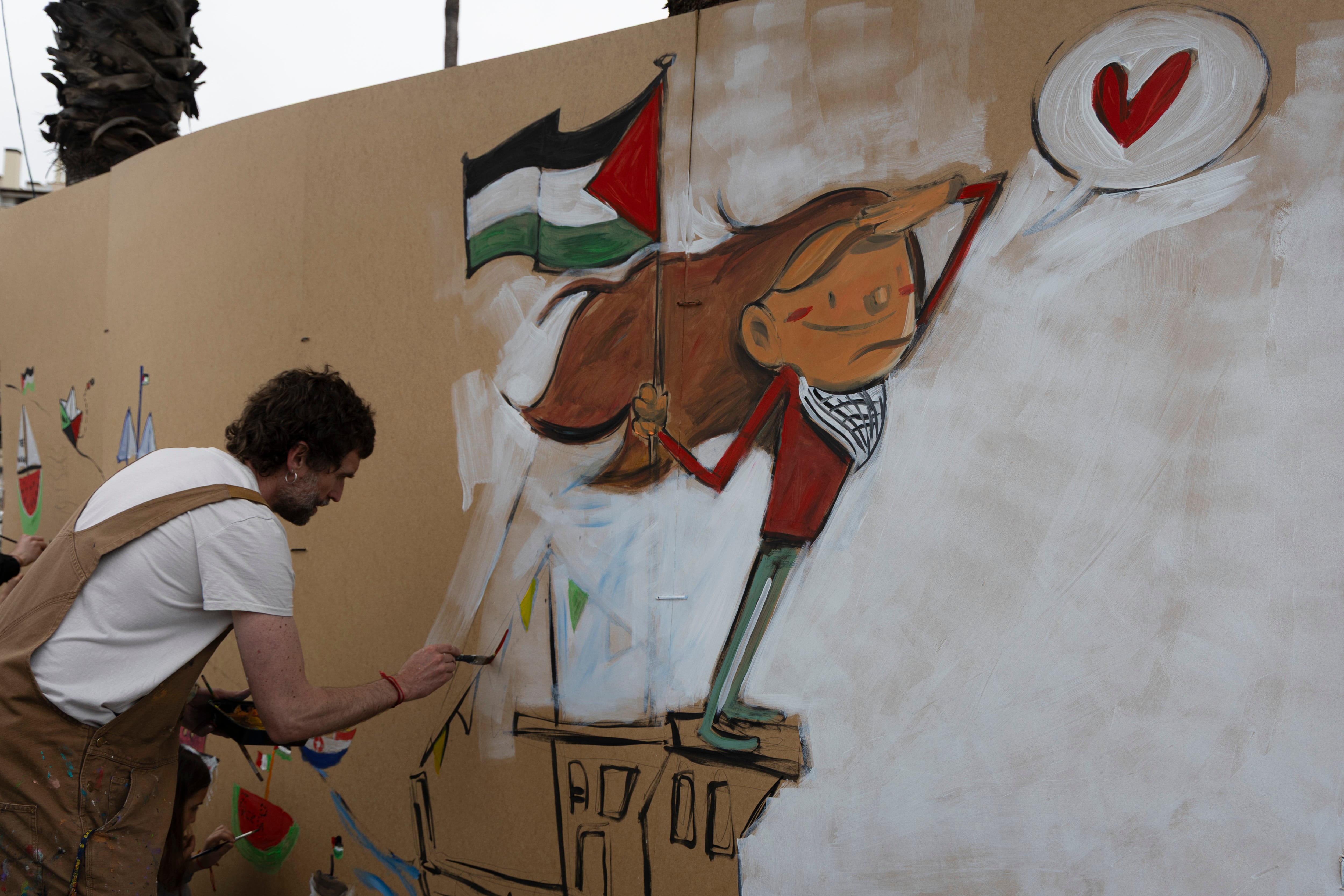Un hombre pintaba un mural a favor de Palestina, este domingo en el puerto de Barcelona.