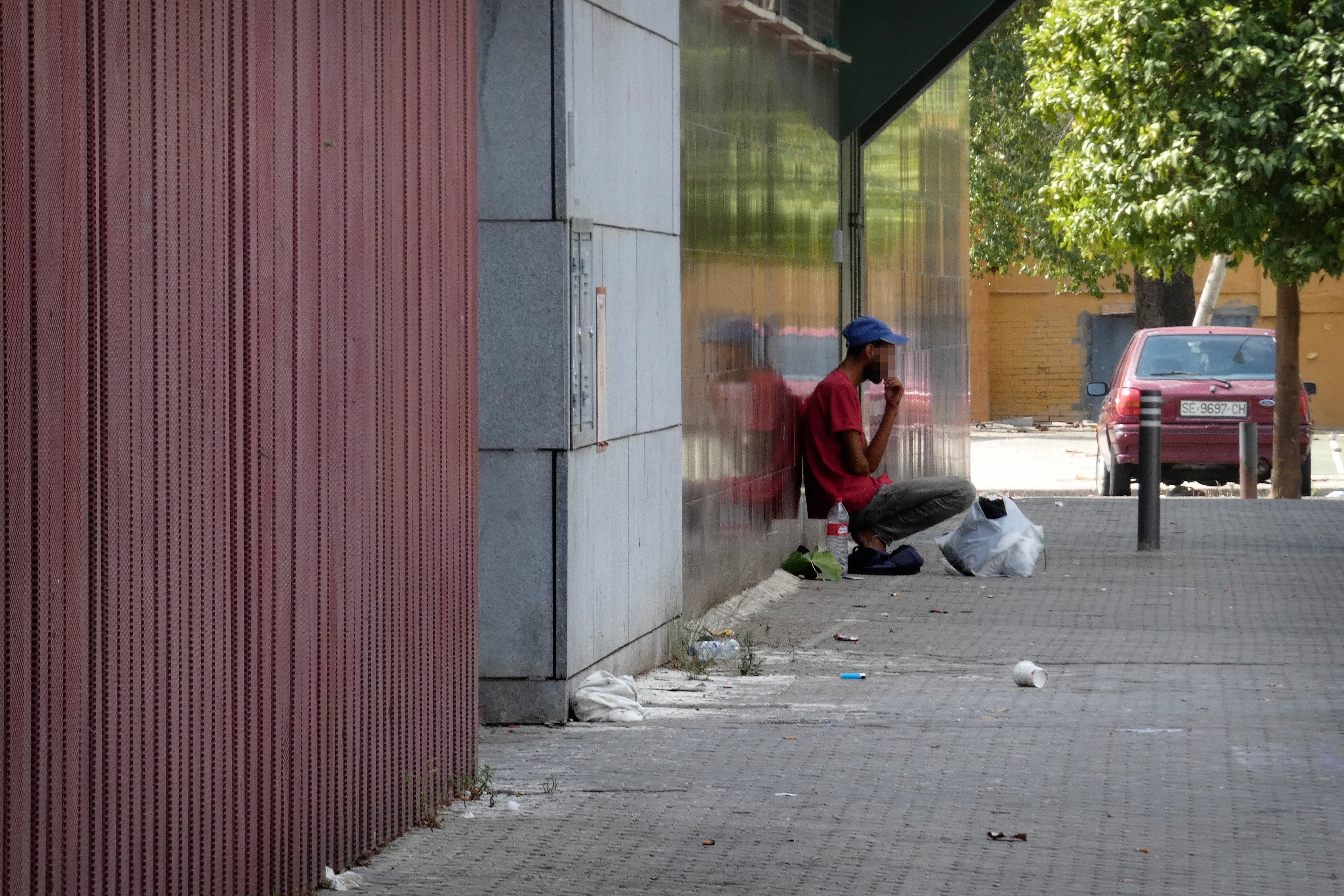 Un joven sentado en la calle junto al centro de salud de Letanías, en el Polígono Sur de Sevilla.