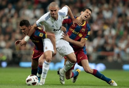 Pepe intenta zafarse de las presión de Villa y Busquets.