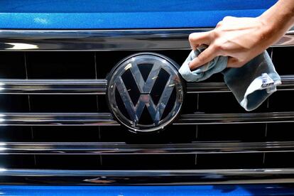 A staff member cleans the logo of a SUV VW Touareg on display ahead of the annual general meeting of German carmaker Volkswagen, in Berlin on May 3, 2018. / AFP PHOTO / Tobias SCHWARZ