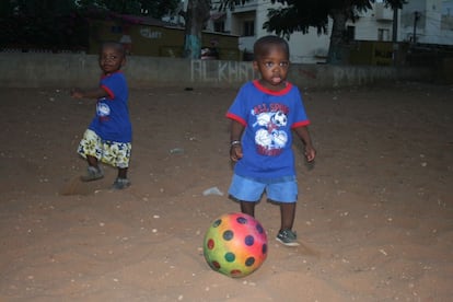 Los hermanos juegan con la pelota en el campo de fútbol que se encuentra junto a su casa, en el barrio de Liberté 1.