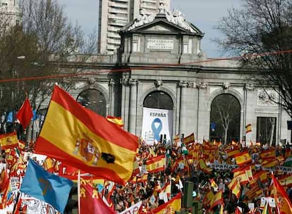 Varias personas se preparan, con banderas y carteles, para participar en la manifestación convocada por el PP en Madrid.